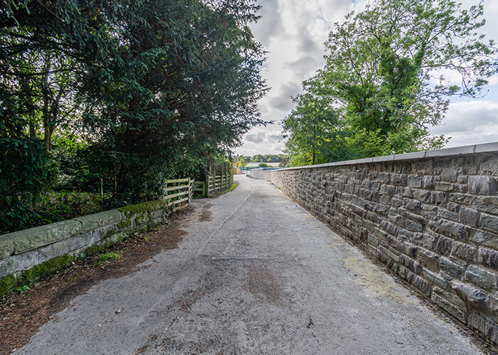 View along narrow road with newly constructed Masonry Solutions Ltd stone wall on right.
