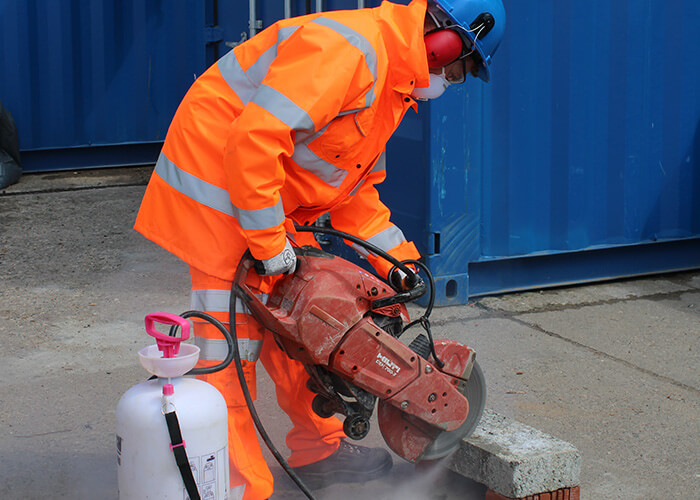 Masonry Solutions Ltd employee in orange work clothing saw cutting stone